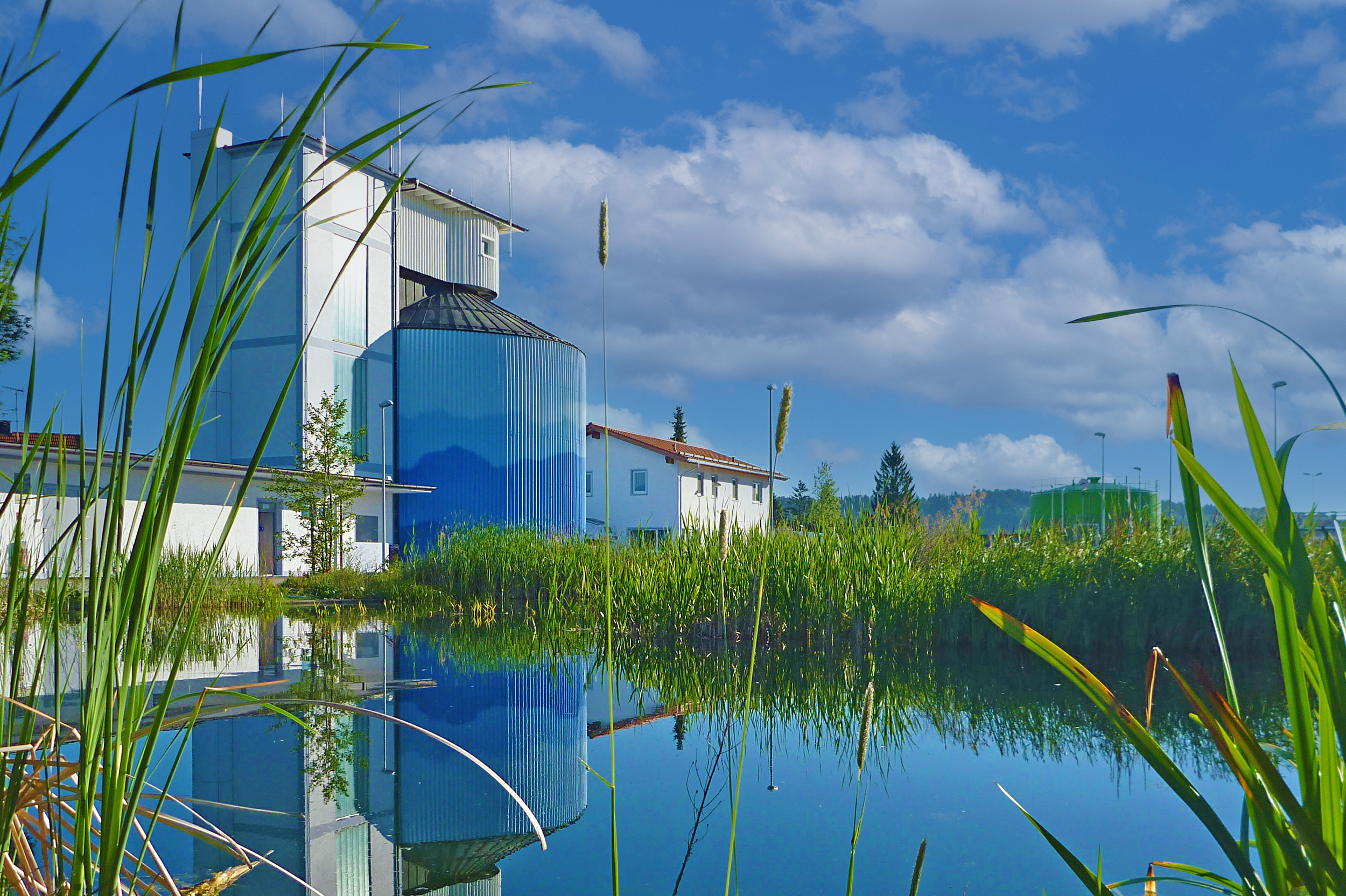 Kläranlage mit naturnah gestaltetem Wasserbecken und technischer Infrastruktur.